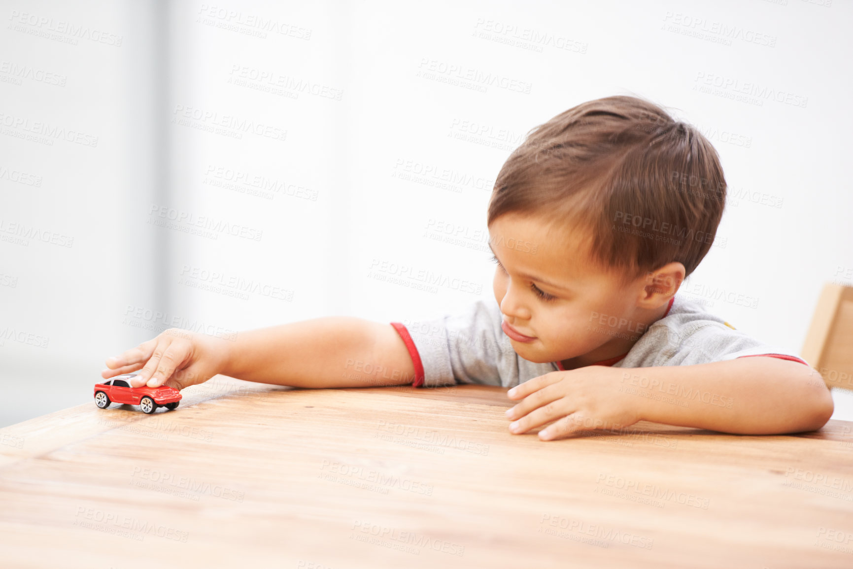 Buy stock photo Shot of a cute young boy playing with a toy car