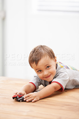 Buy stock photo Cars, toys and portrait of child by table playing for learning, development and fun at modern home. Cute, sweet and boy kid enjoying a game with plastic vehicles by wood for childhood hobby at house.