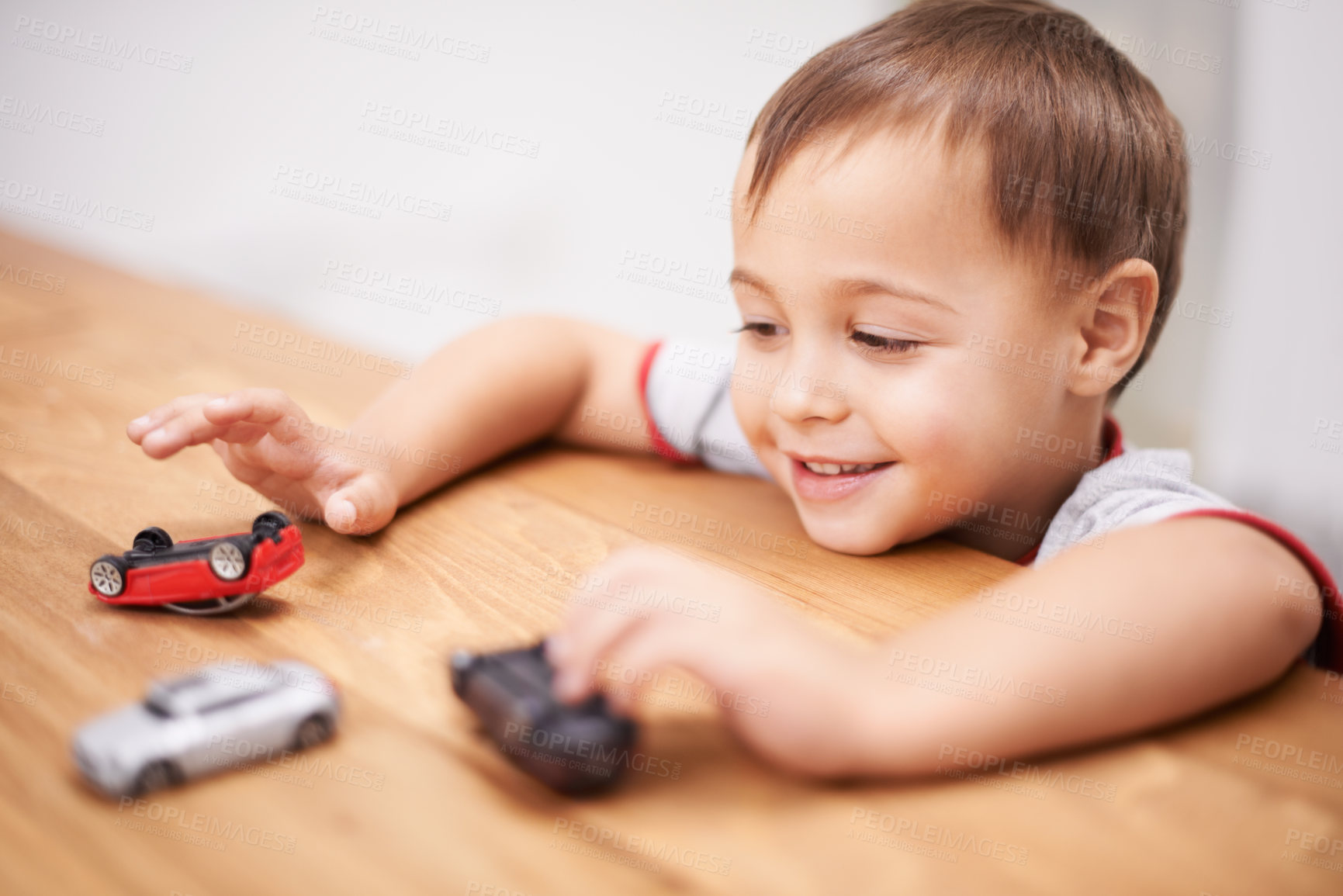 Buy stock photo Cars, toys and boy kid by table playing for learning, development and fun at modern home. Cute, sweet and young child enjoying a game with plastic vehicles by wood for childhood hobby at house.