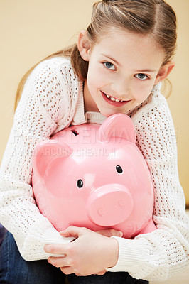 Buy stock photo Cropped portrait of a cute little girl smiling while holding a piggybank