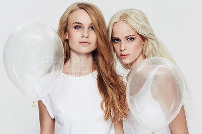 Buy stock photo Studio portrait of two young woman holding clear balloons
