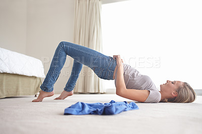 Buy stock photo A young woman struggling to pull on her jeans