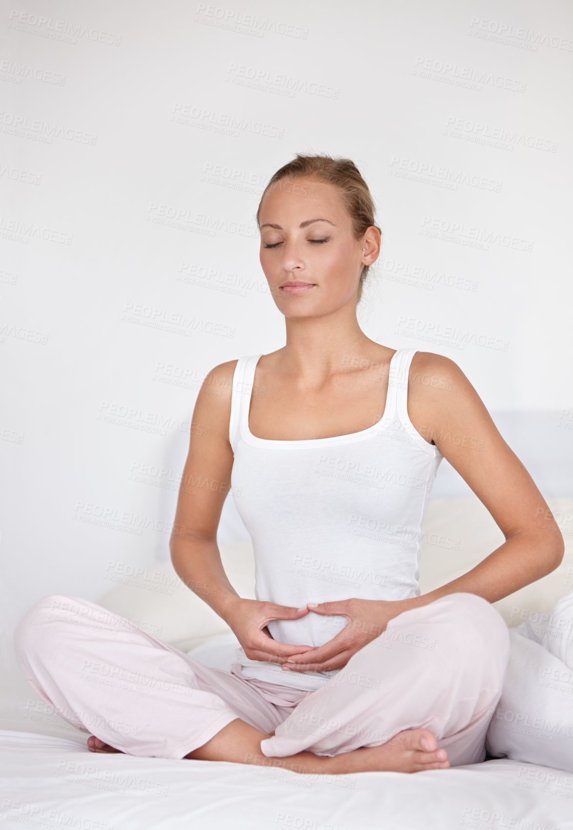 Buy stock photo Calm woman, relax and spiritual wellness on bed for health, chakra or morning wakeup at home. Young female person holding stomach or tummy in zen, meditation or awareness sitting in bedroom at house