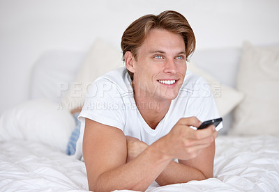 Buy stock photo Man, movie and watching tv in bed with happiness and remote in the morning for streaming, entertainment and relax. Happy young male person with television series, news and digital control in bedroom 