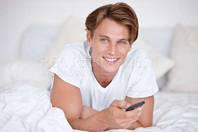 Buy stock photo Man, portrait and watching tv on a bedroom bed with happiness and remote in the morning. Happy, smile and young male person with series and movie with digital control in a house with television