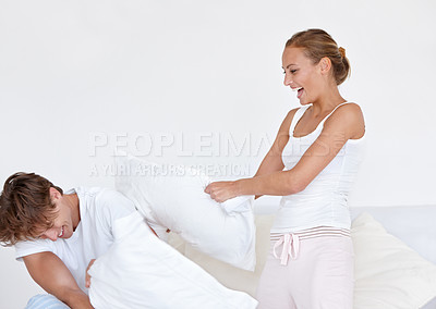 Buy stock photo Happy, fun and couple in a pillow fight on the bed in the hotel room on a romantic weekend trip. Happiness, laughing and young woman and man playing together in the morning in the bedroom at home.