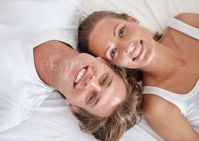 Buy stock photo Cropped view of a young couple lying in bed and looking up