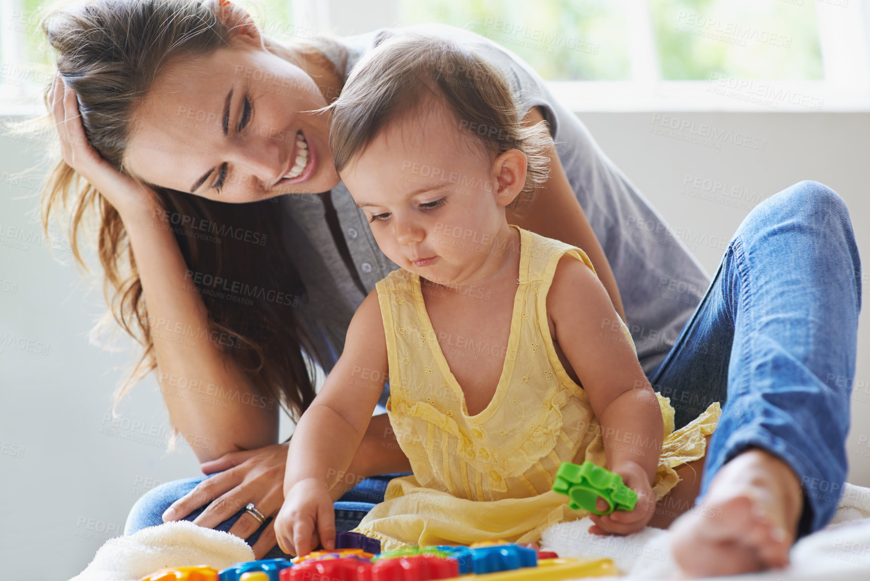 Buy stock photo Shot of a cute baby girl sitting on the floor with her mom and playing with toys