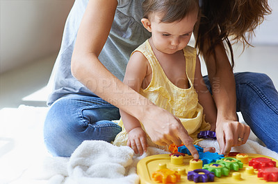 Buy stock photo Shot of a cute baby girl sitting on the floor with her mom and playing with toys
