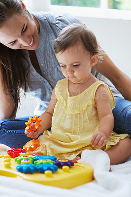 Buy stock photo Shot of a cute baby girl sitting on the floor with her mom and playing with toys