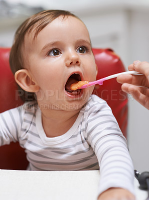 Buy stock photo Shot of a cute little baby sitting in a high chair and being fed by her mom