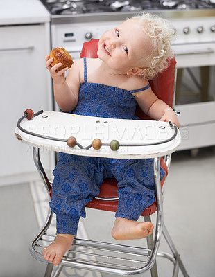 Buy stock photo A sweet little baby eating a muffin while sitting in her high chair