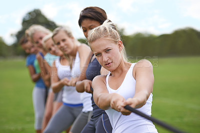 Buy stock photo Shot of a group of young woman engaged in a tug of war