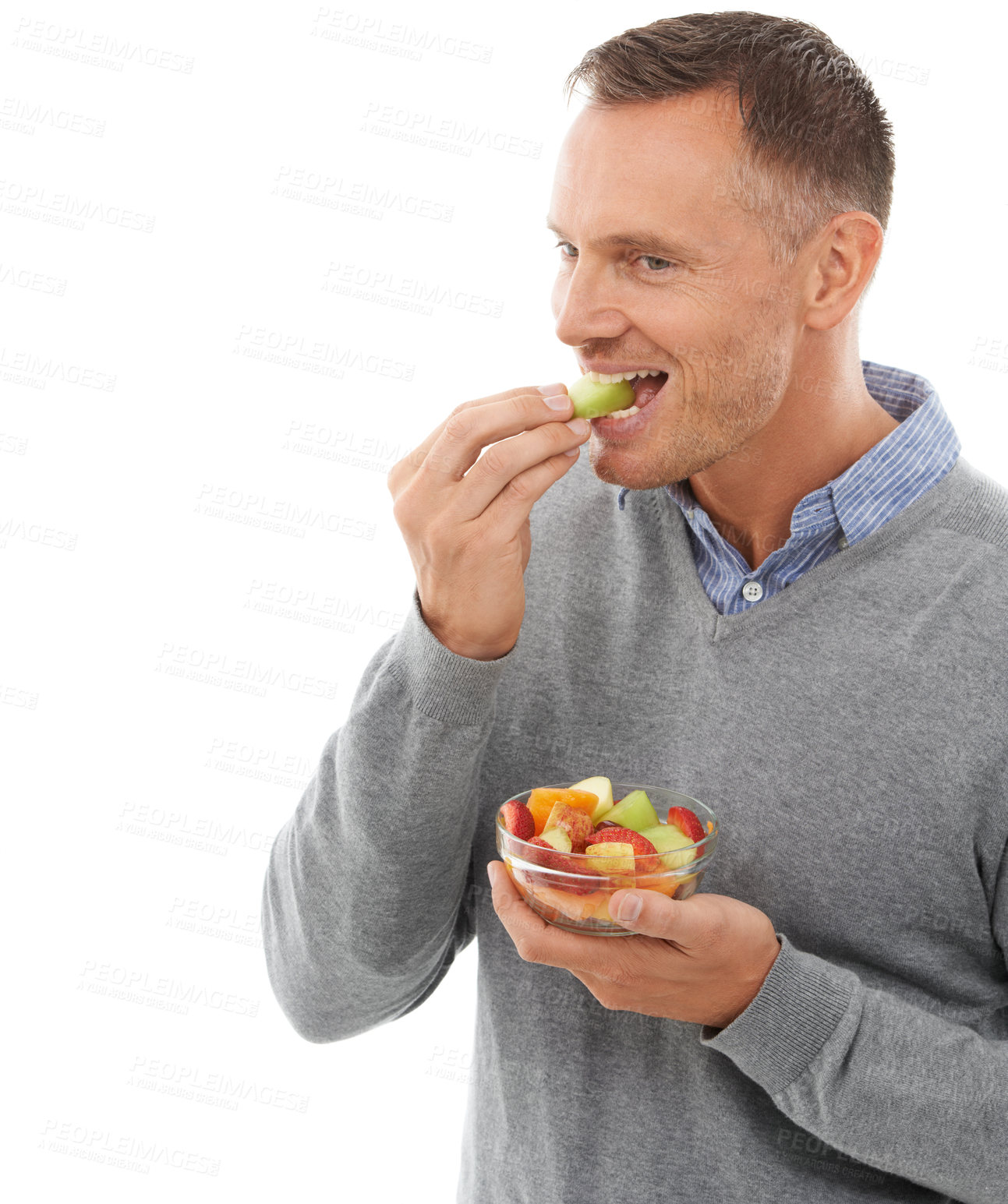 Buy stock photo Mature man eating fruits isolated on a white background for healthy green lunch, diet choice or nutritionist breakfast. Professional vegan person or model with fruits salad, food or apple in studio