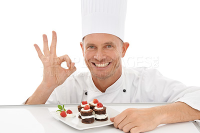 Buy stock photo Perfect, sign and dessert chef happy with dish or sweet chocolate flavor with hand gesture isolated in studio white background. Portrait, smile and plate of food by a culinary cook with mini cakes