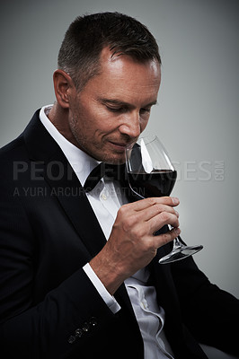 Buy stock photo Tuxedo, wine glass and man with alcohol in a suit feeling classy with a luxury drink. Gray background, isolated and studio with a model, agent or actor with a glass to smell rich wines with mockup