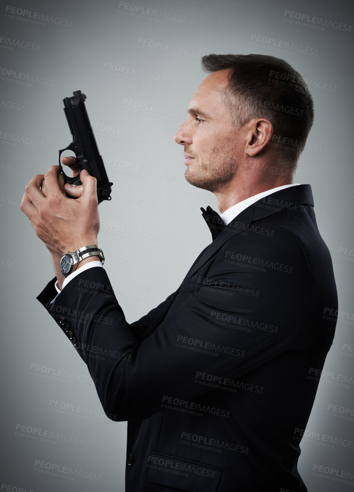 Buy stock photo Agent man, profile and gun with suit for mission, justice or espionage by grey studio background. Government spy, detective and firearm with designer tuxedo, secret information and undercover work