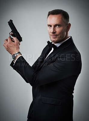 Buy stock photo Portrait, gun and man in studio with weapon for power, crime or secret mission on grey background. Face, handgun and mature guy model ready to shoot with mockup, assassin or hitman aesthetic isolated