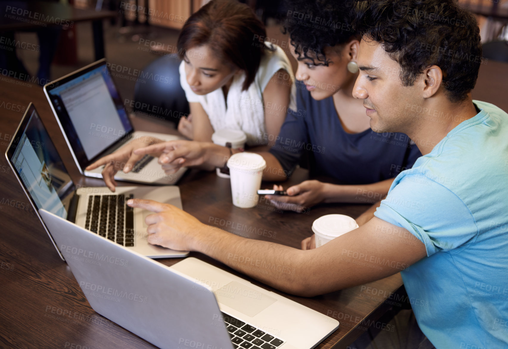 Buy stock photo A group of students using a laptop to complete a group assignment