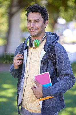 Buy stock photo Young man, headphones and book on campus and scholarship opportunity in commitment at college. Student, smile and audio electronics by backpack, relax and university outdoor for learning in nature