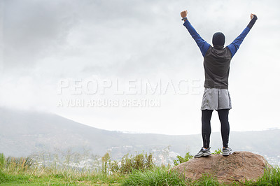 Buy stock photo A young man celebrating at the top of a mountain after reachin
