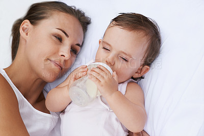 Buy stock photo Baby, mother and drinking bottle for nutrition, liquid food and  relaxing together on bed at home. Mommy, toddler and formula for health or child development in bedroom, feeding and milk for wellness