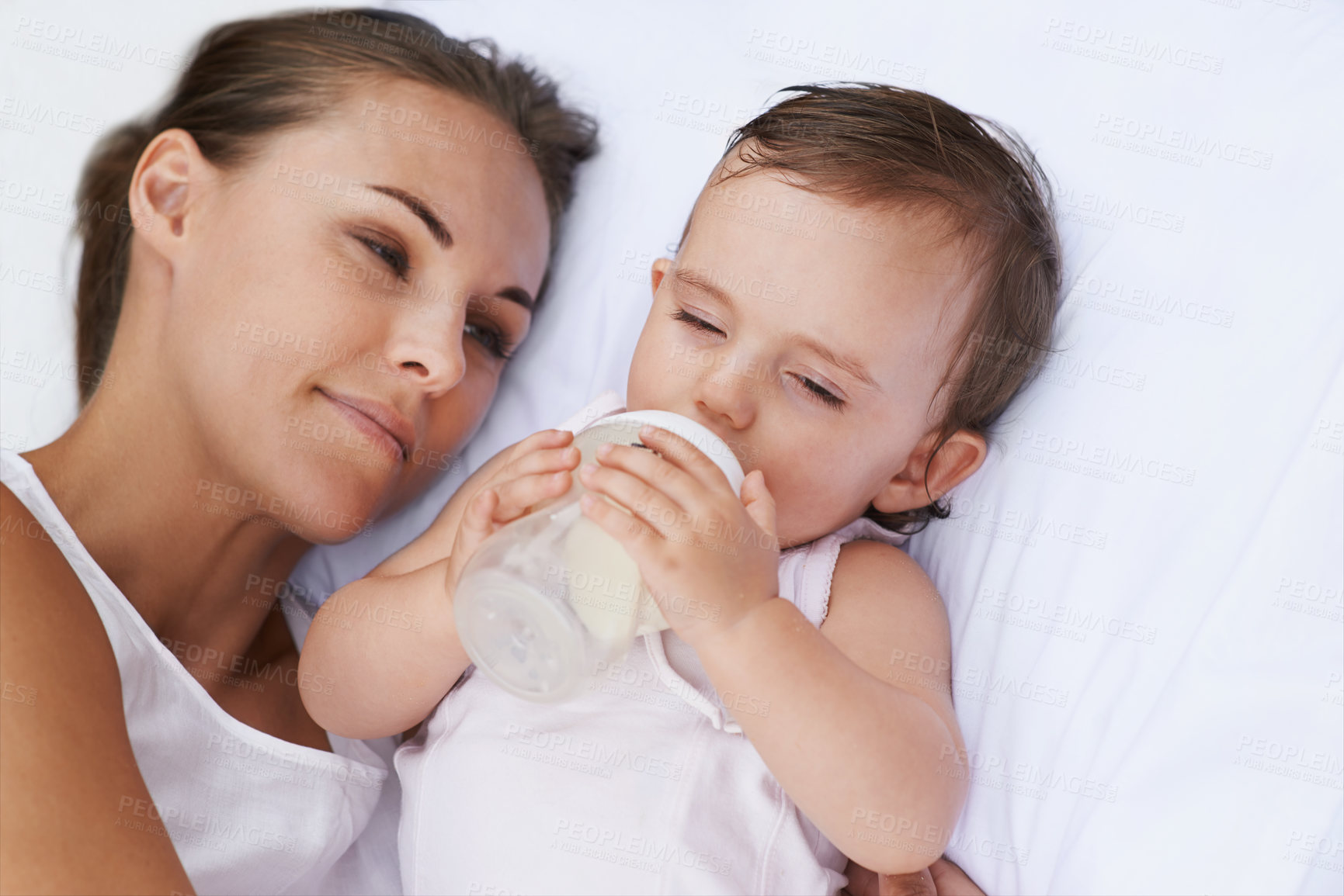 Buy stock photo Baby, mother and drinking bottle for nutrition, liquid food and  relaxing together on bed at home. Mommy, toddler and formula for health or child development in bedroom, feeding and milk for wellness