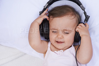 Buy stock photo Baby, headphones and streaming music to relax, radio and listening to podcast on bed at home. Girl, kid and hearing sound for child development or learning, toddler and calming playlist for audio