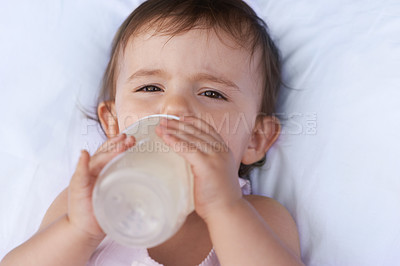 Buy stock photo Baby, portrait and drinking milk for nutrition, liquid food and  relax on bed at home. Girl, toddler and formula for health or child development in bedroom, feeding and bottle for wellness and growth