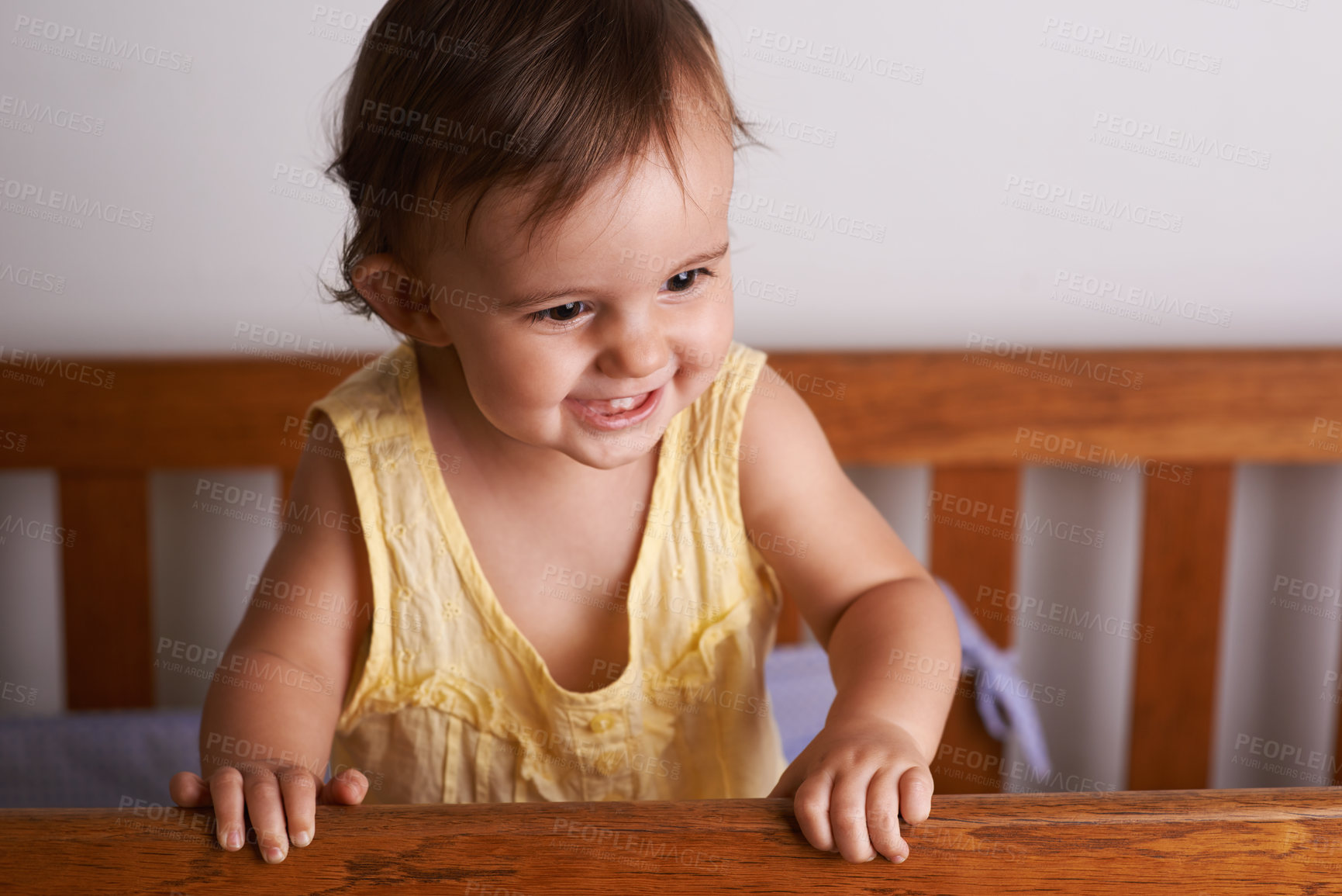 Buy stock photo Baby in crib, playing with smile and fun in home, child development and care in home. Excited toddler girl in cot with playful face, energy and happiness in cute kids bedroom, nursery or apartment