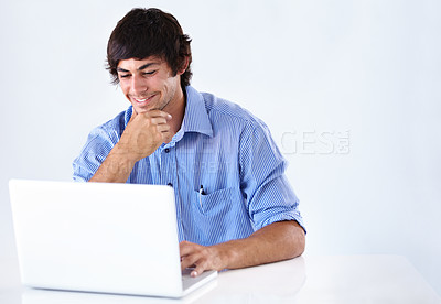 Buy stock photo Shot of a smiling young businessman working at a laptop