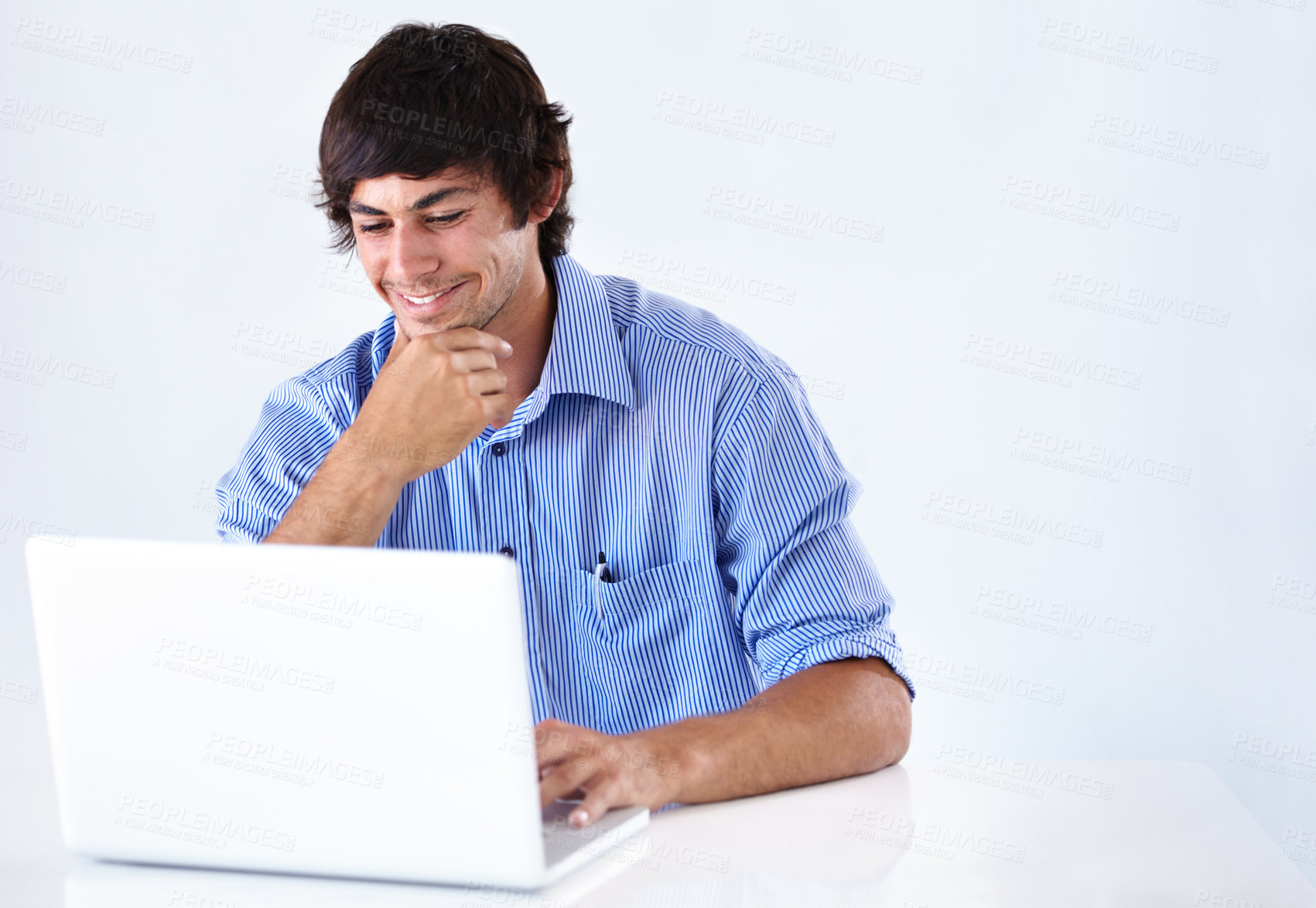 Buy stock photo Shot of a smiling young businessman working at a laptop