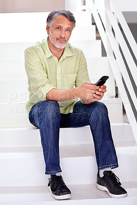 Buy stock photo A mature businessman using his cellphone while sitting in the office