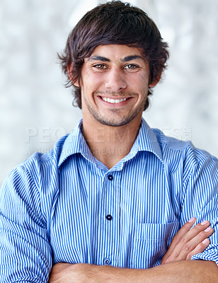 Buy stock photo A handsome young man standing with his arms folded