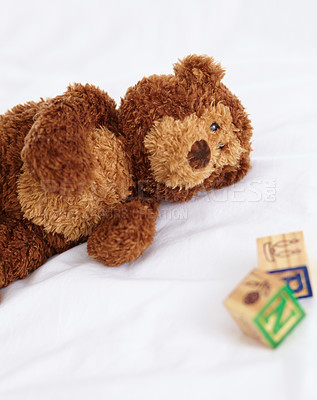 Buy stock photo Teddy bear, toys and closeup in bedroom with building blocks on a mattress for still life of development. Learning, letters and objects for childcare and play in home with soft animal and alphabet