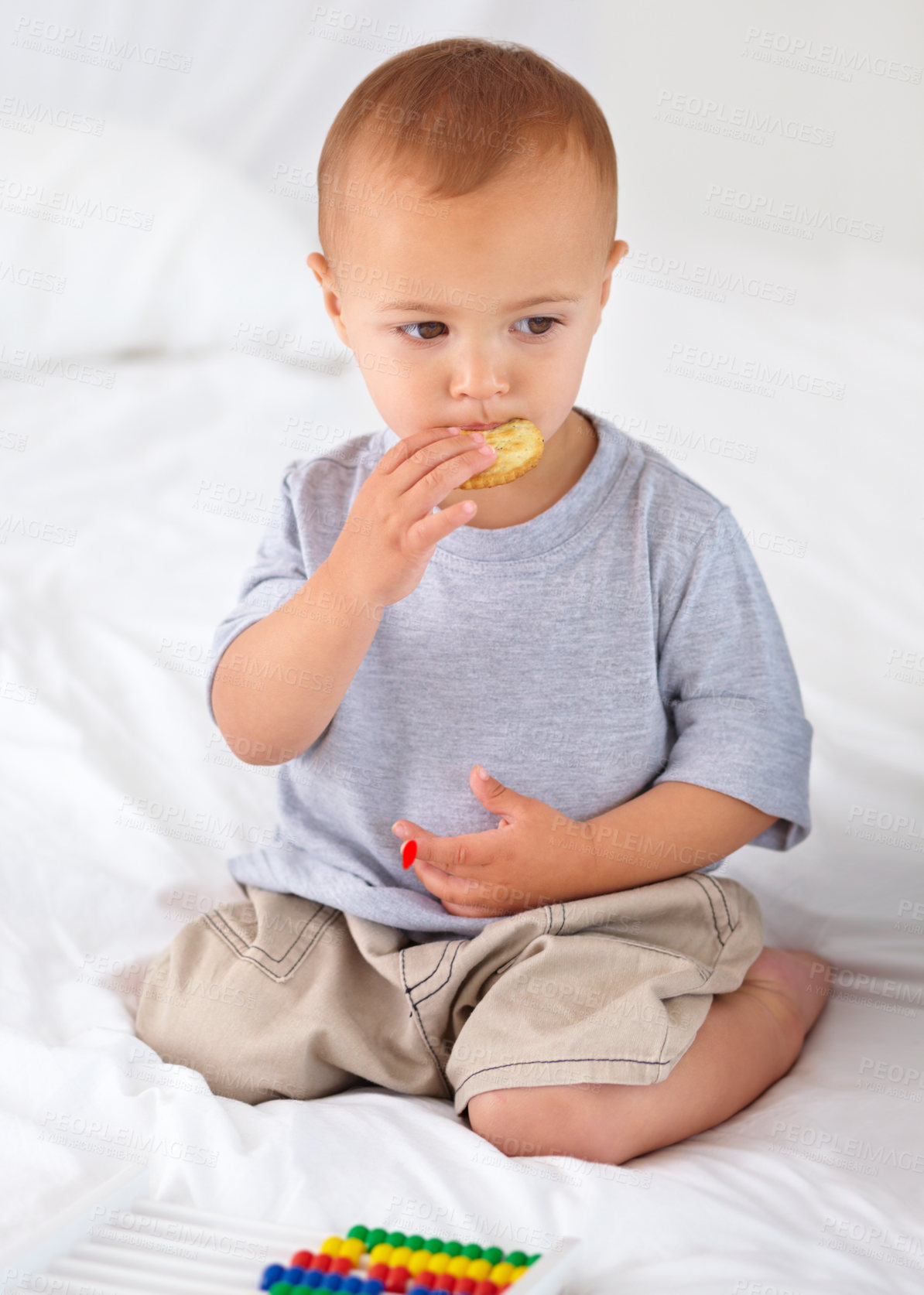 Buy stock photo Cute, bed and baby eating biscuit for yummy snack playing with abacus for education. Child development, sweet and hungry young boy kid, infant or toddler enjoying a cracker in bedroom at home.