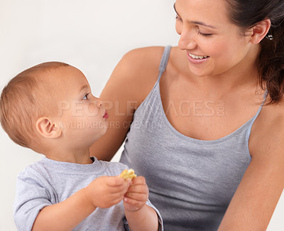 Buy stock photo Bonding, bed and mother with baby eating biscuit for yummy, delicious and nutrition snack. Child development, love and young mom with boy kid, infant or toddler enjoying a cracker in bedroom at home.