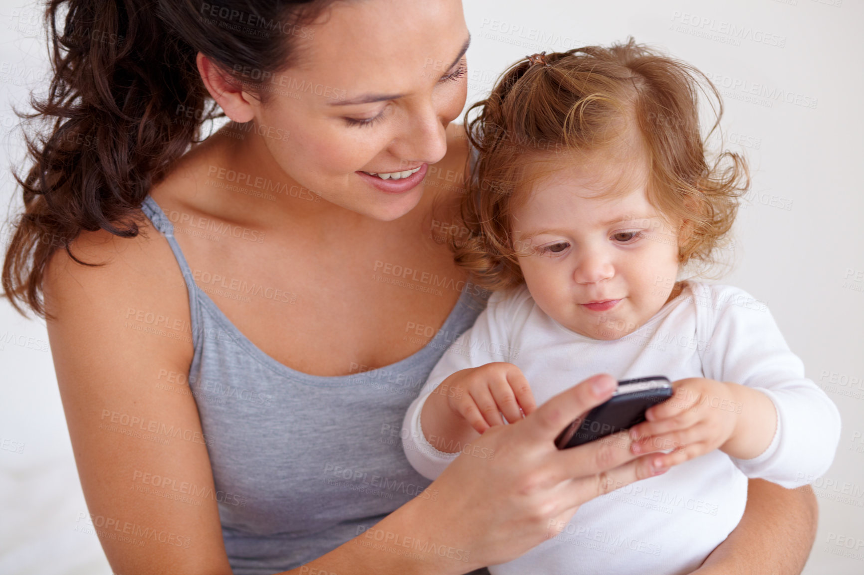 Buy stock photo Cellphone, playing and mother with baby on bed for bonding and watching video on social media together. Happy, love and young mom scroll on a phone with girl child, kid or toddler in bedroom at home
