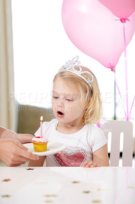 Buy stock photo Shot of a cute young girl blowing out a candle on a cupcake
