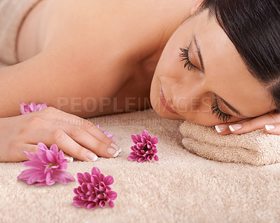 Buy stock photo Cropped view of a young woman relaxing at a spa with a fresh flower nearby