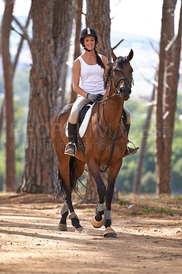 Buy stock photo A beautiful young woman smiling while riding her chestnut horse
