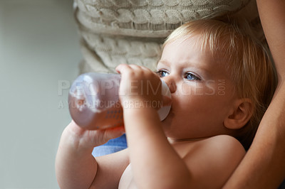 Buy stock photo A baby boy drinking from his bottle while being held by his mother