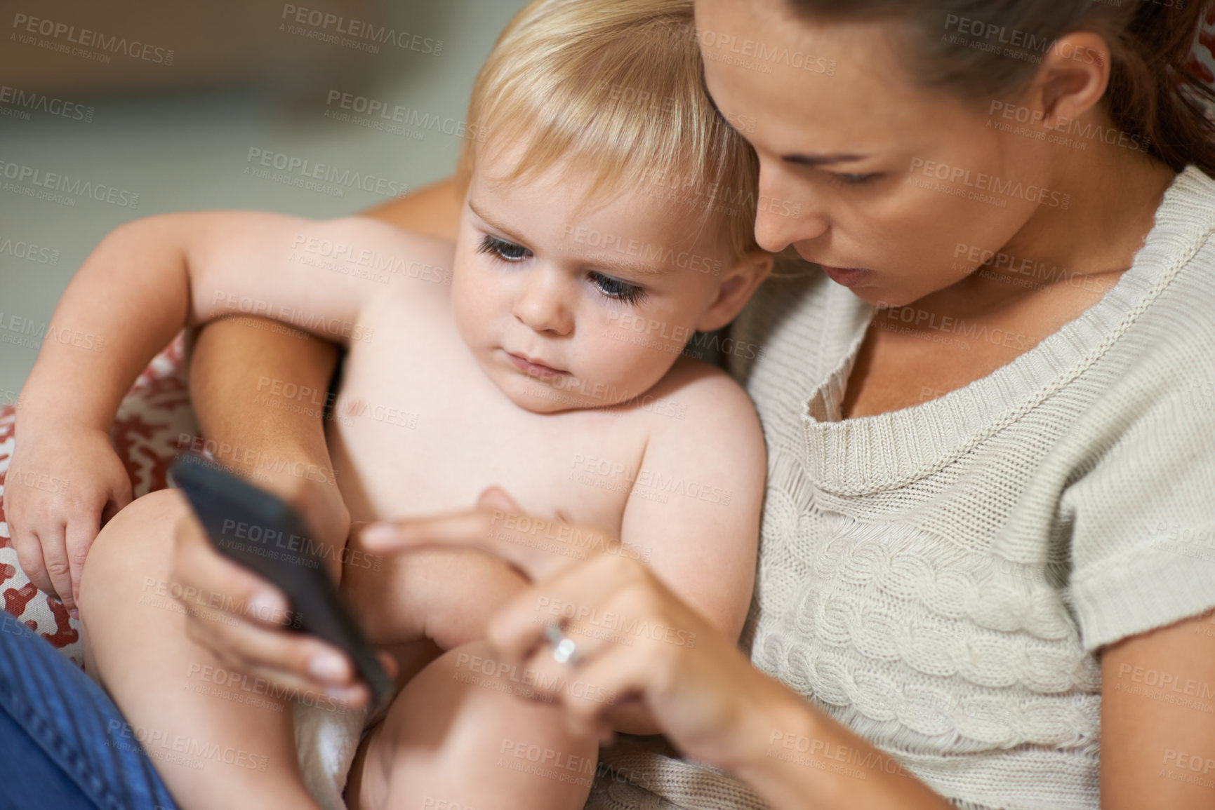 Buy stock photo A mother showing her baby boy something on her cellphone