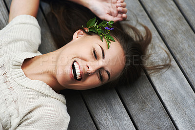 Buy stock photo Woman, face and happy on porch for relax outdoor in backyard with flower, lying down and rest in home. Person, spring and smile on wooden deck in garden of house or apartment with carefree or casual