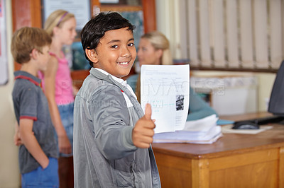 Buy stock photo Portrait, child and student with thumbs up and paper for test or assignment in classroom. Happiness, hand gesture and kid with like emoji, agreement and learning in elementary school for education.