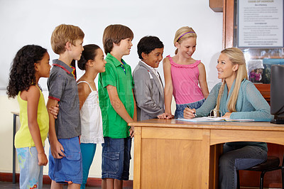 Buy stock photo Teacher at desk, students and education with learning for growth and development in classroom. Woman, children and diversity, school and scholarship with feedback, academic and study in class