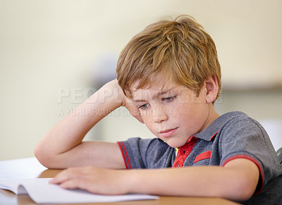 Buy stock photo School, education and a boy reading a book at his desk in a classroom for studying or child development. Kids, learning and bored with a young male student child in class to study for an exam or test