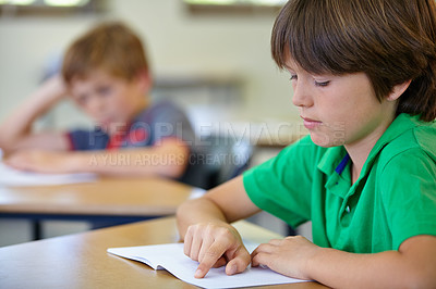 Buy stock photo Class, notebook and child at desk, learning and education with attention on school exam project. Reading book, studying for test and boy student in classroom with knowledge, information and thinking.