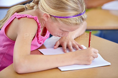 Buy stock photo Girl, school and writing in classroom with notebook, studying lesson and learning assessment at desk. Child, student and kid drawing on paper for academic development, educational test and knowledge
