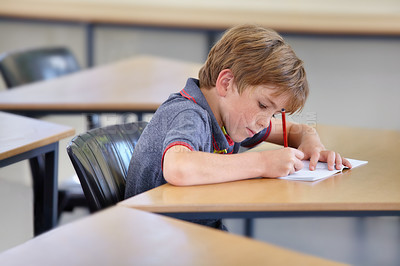 Buy stock photo Boy, notebook and writing in school, classroom or studying academic assessment, learning lesson or test at table. Student, child and kid drawing notes on paper for education, development or knowledge